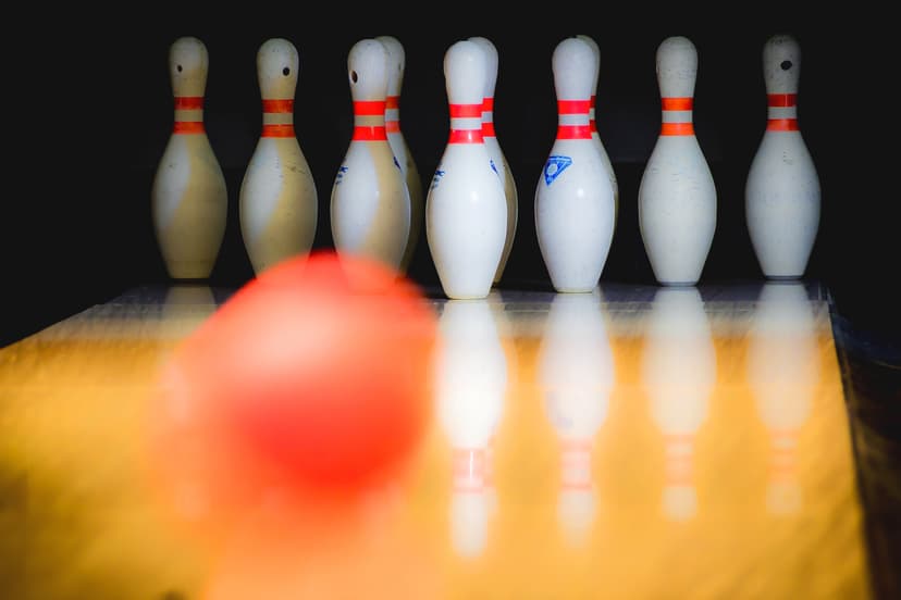 Rött bowlingklot rullar mot käglor på en bowlingbana