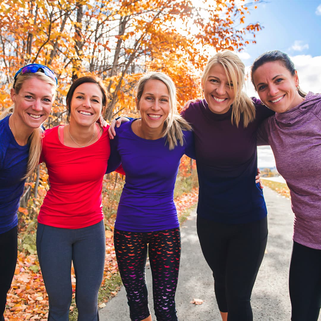 Fem kvinnor med träningskläder och träd med höstlöv i bakgrunden